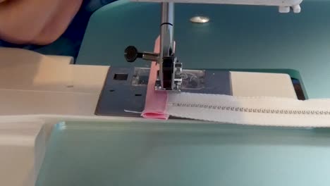 A woman sews fabric stops at ends of metal zippers
