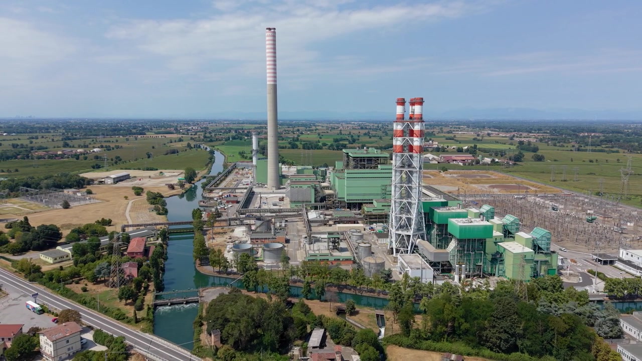 Veduta aerea di una centrale elettrica a gas circondata da attrezzature industriali e infrastrutture di supporto, che rappresenta la scala della moderna generazione di elettricità e delle operazioni di servizio. Italia, Lombardia.