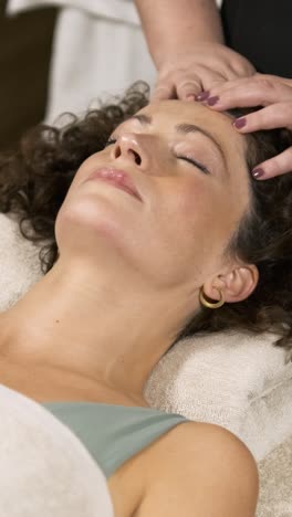 beautician performing facial massage on woman. vertical