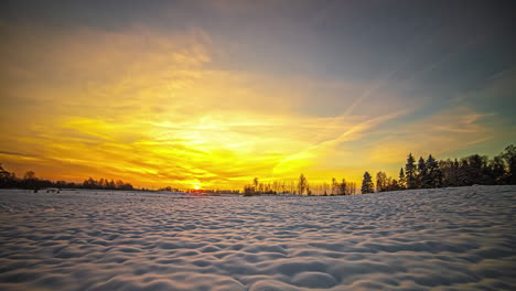 toma de tiempo del paisaje rural cubierto de nieve con el sol saliendo en el fondo sobre el cielo amarillo durante el tiempo de la mañana