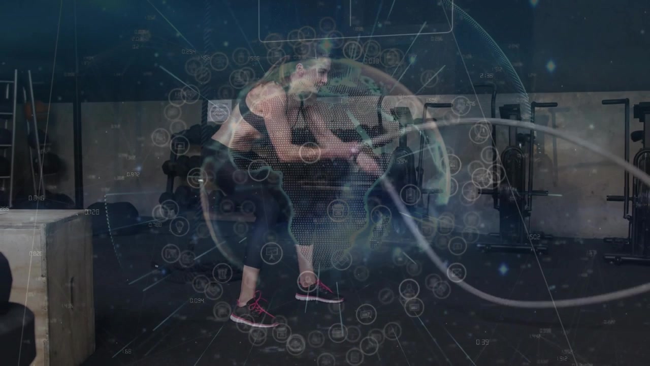 Vertical video: Woman gripping battle ropes, driving waves for fitness in gym, globe HUD circling