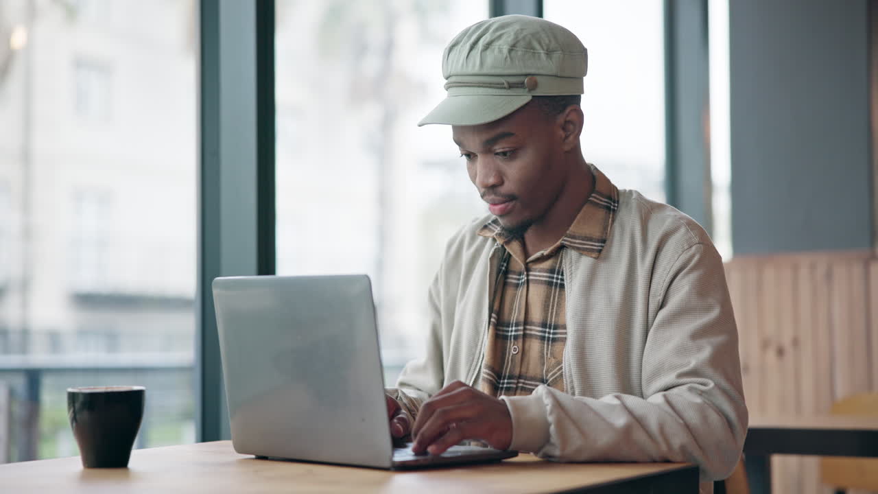 Black man typing on laptop in cafe