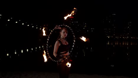chica de fuego elegante realizando trabajo con hula hoop de fuego