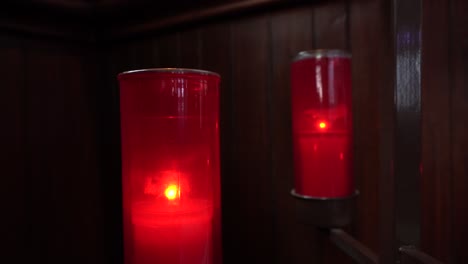 two red candles that burn in a church behind a wood wall