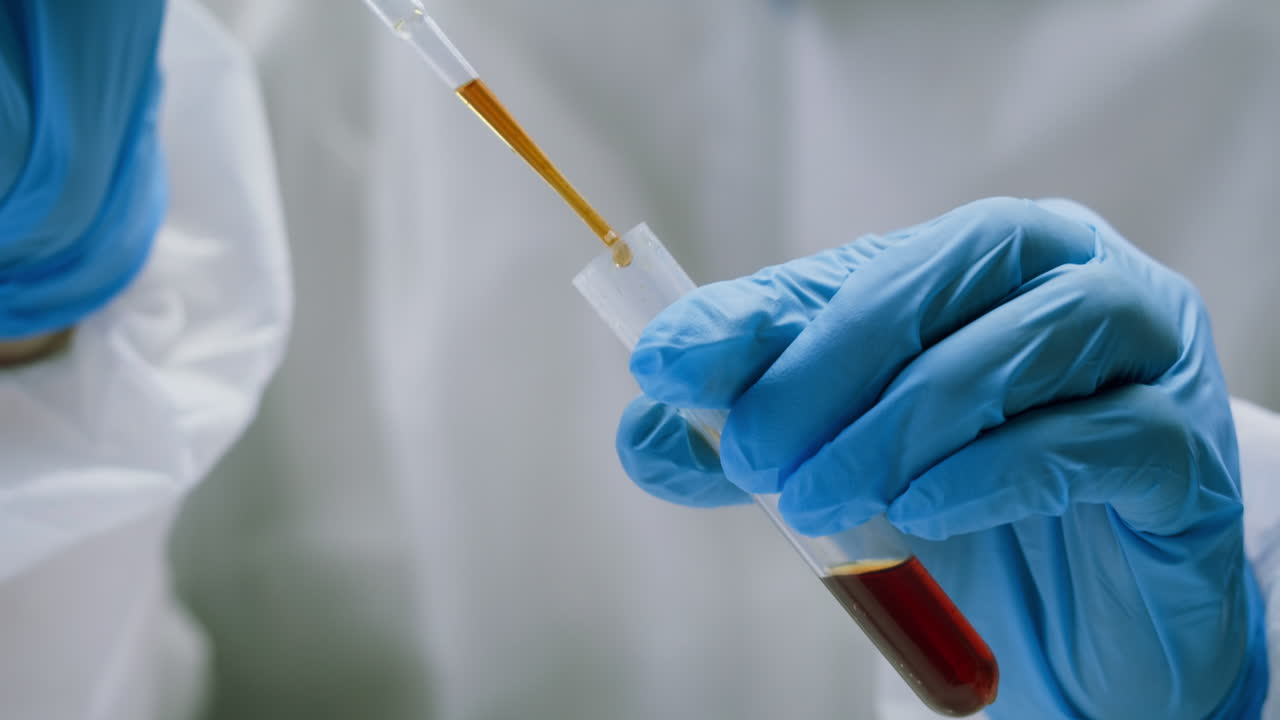 Scientist in Gloves Pipetting Liquid into Blood Sample Test Tube