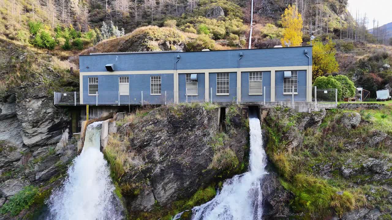 Drone footage captures the Kawarau Gorge hydroelectric station in Queenstown, New Zealand, highlighting the cascading waterfall and rugged landscape