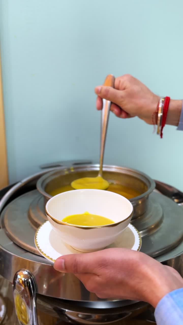 Close-up 4K vertical shot of hot yellow soup being served with a ladle into a ceramic bowl. Ideal for food content, cooking videos, restaurant promos, or social media reels.