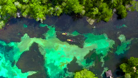 Volando-Lentamente-Sobre-El-Cristalino-Río-Arcoíris-Con-Kayaks-Y-Nadadores-Debajo