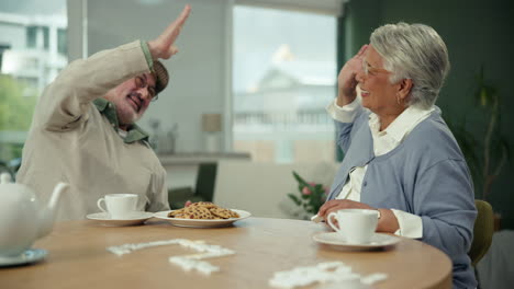 senior couple celebrating and playing dominoes during tea party