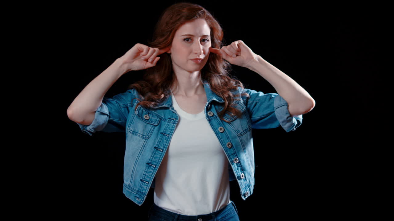 젊은 백인 여성이 귀를 막고 있습니다.