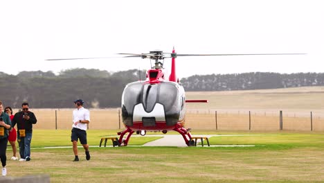 red helicopter landing on a field