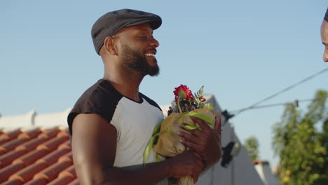 medium shot of happy bearded gay taking flowers from lover