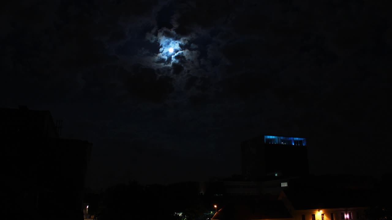 밤에 구름 뒤에 숨어있는 달, 한 개의 마천루를 볼 수 있습니다.