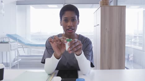 African-american-female-doctor-holding-medication-and-making-video-call-in-hospital,-slow-motion