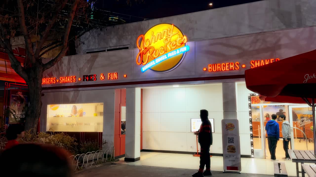 Tilt up of a Johnny Rockets themed restaurant, hamburger restaurant at night, high chairs with lights, Fantasilandia amusement park, Santiago de Chile.