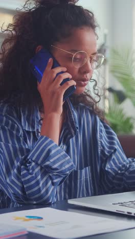 young indian woman financier in casual clothes makes call sits in home office