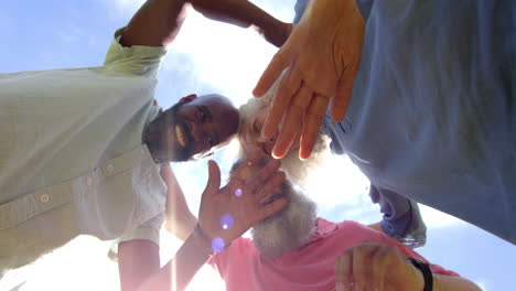 smiling senior friends embracing and looking down at camera outdoors