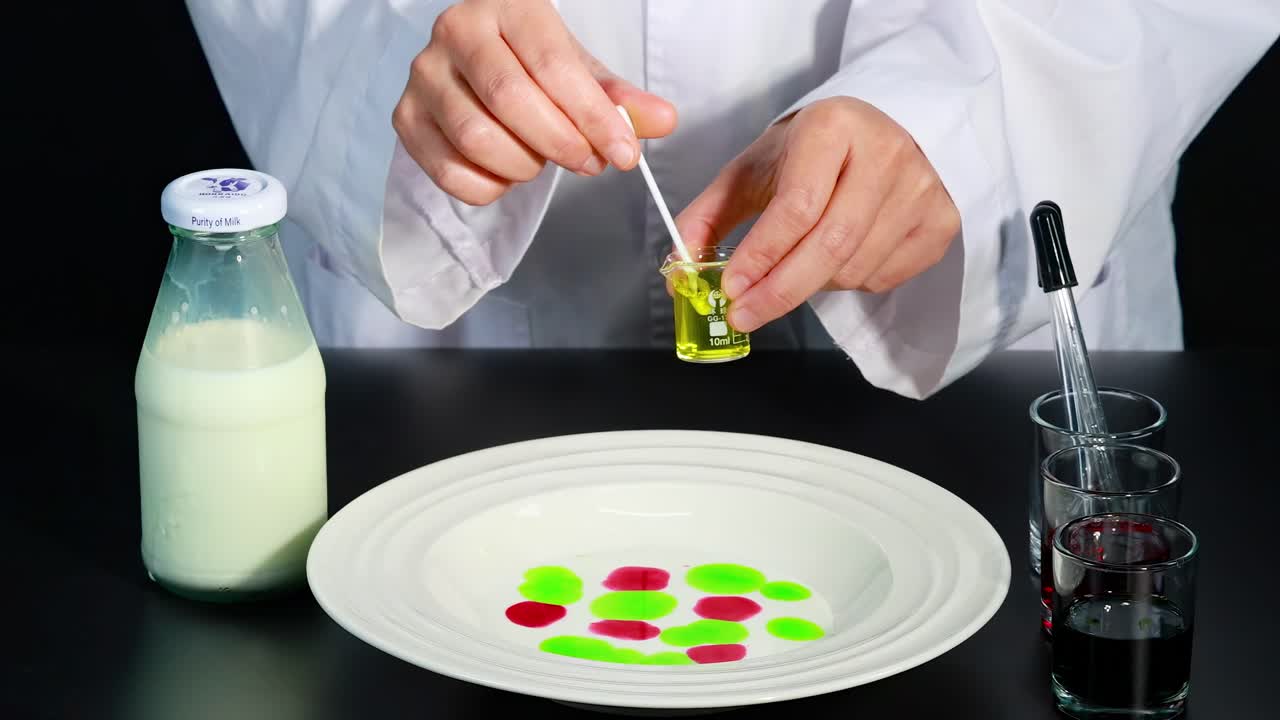 Observe a vibrant color transformation in milk using droppers and swabs, creating mesmerizing patterns.