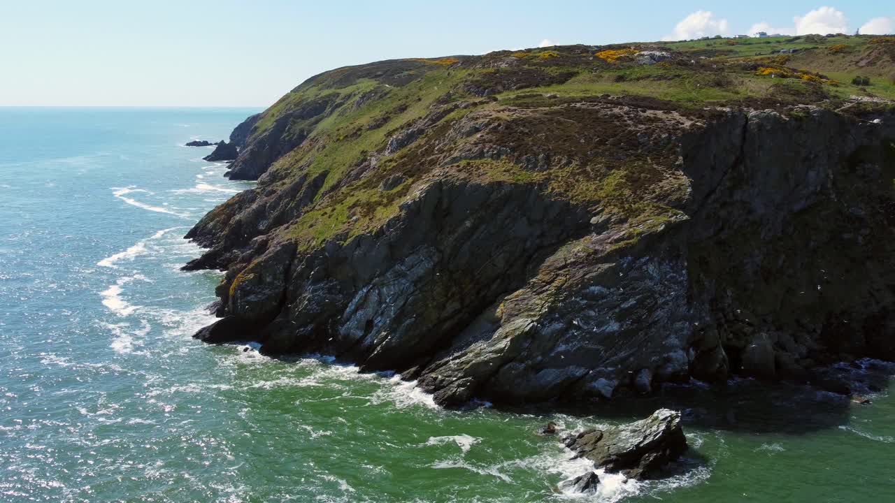 Aerial view of rocky coast and cliffs with flying seagulls in bright, sunny day