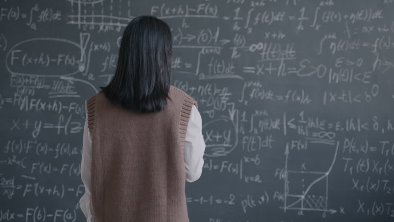 Woman Teacher Writing Equations on a Chalkboard