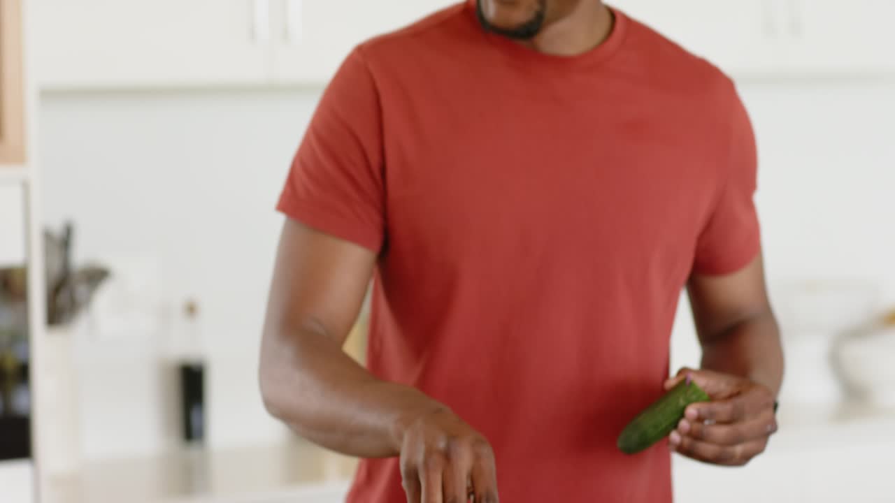 African American couple scraping shallots into pan and stirring spatula at stovetop to prepare meal