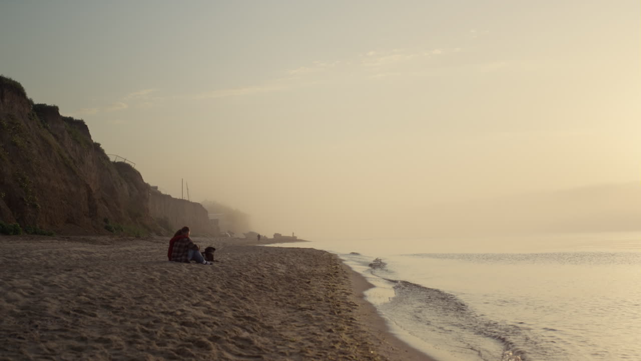 una pareja romántica sentada en la orilla del mar al amanecer. una mujer encantadora abrazando a un hombre