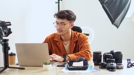 male photographer types on laptop and preparing for photo shot