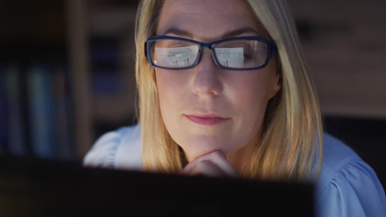 Video of focused caucasian woman using computer, working late in office