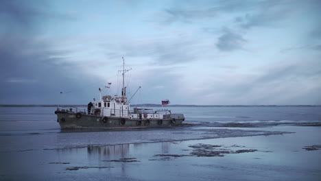tugboat breaking ice on a river in winter