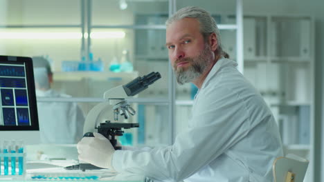 portrait of senior scientist with microscope in lab
