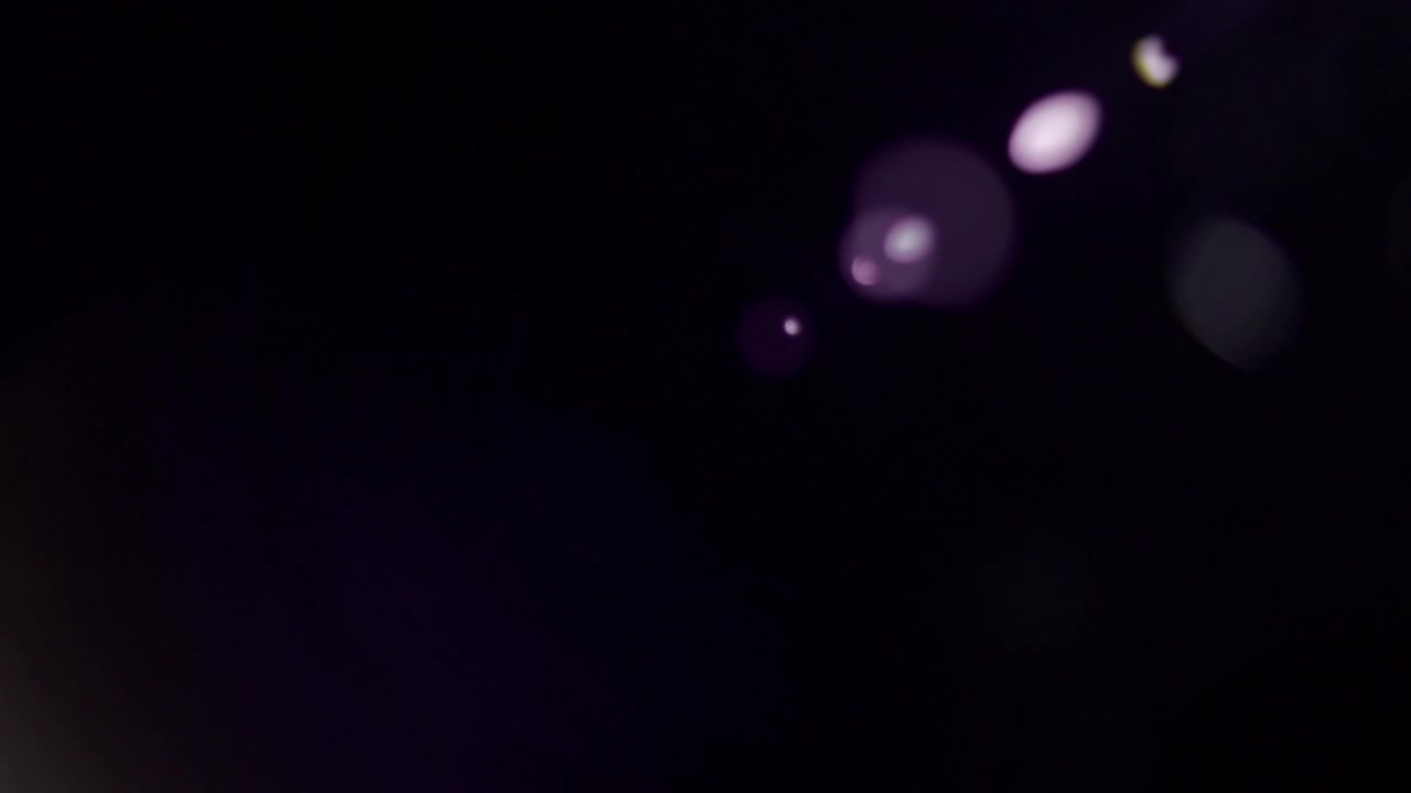 Lens flare viola astratti in movimento su sfondo scuro