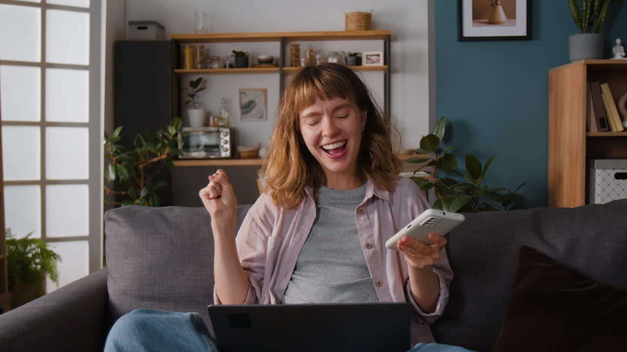 Woman using laptop and phone on couch