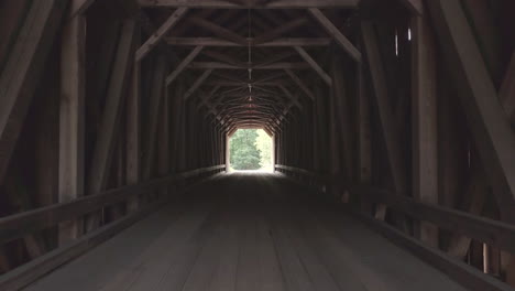 pushing in slowly through the dark, dramatic wooden tunnel of the public lowes covered bridge in maine