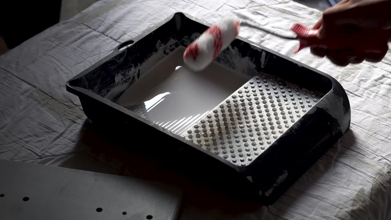 페인트 롤러를 사용하여 페인트를 사용하기 전에 페인트로 적시는 백인 남성