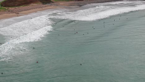 Drone-shot-flying-over-surfers-in-the-pacific-ocean-with-large-waves