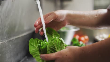 Close-up-of-caucasian-female-chef-washing-vegetables-in-restaurant-kitchen