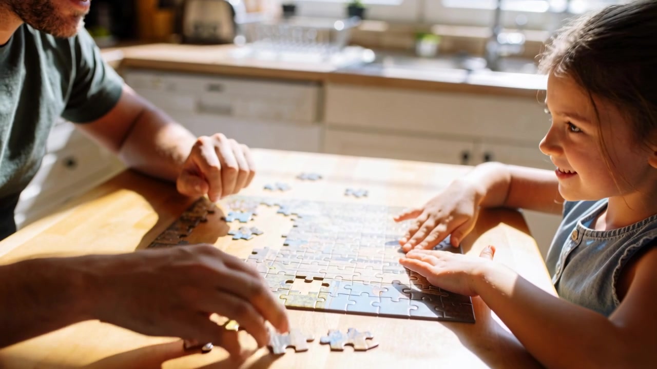 Incastrando pezzi di puzzle, padre e figlia si danno il cinque, poi riprendono l'assemblaggio del puzzle in cucina.