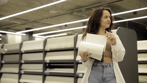 A young woman buys wallpaper to update the design of her apartment.