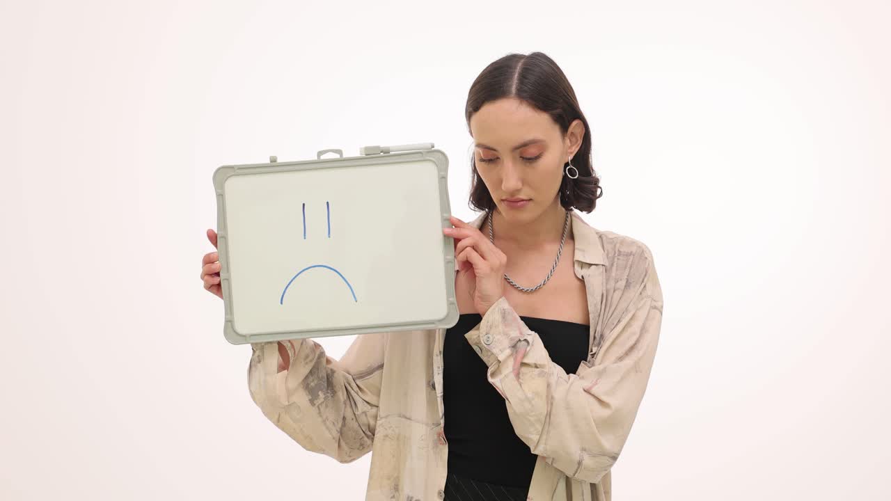 Woman showing a sad face on a whiteboard