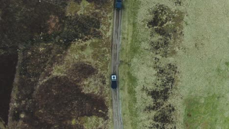 2 off road vehicles driving down quiet secluded track from top down aerial view