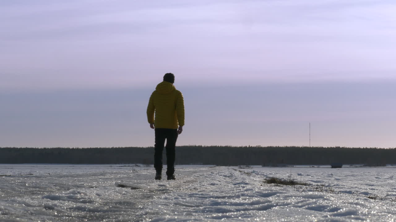 hombre caminando en un paisaje de nieve plano desierto en vista trasera estática