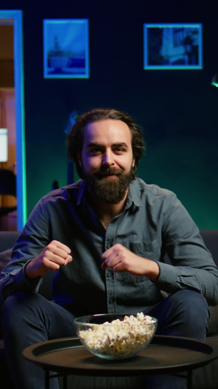 Vertical video Ecstatic man watching sports broadcast at home, doing frantic hand gesturing