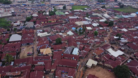 Stunning aerial of a large shanty town at the edge of Abuja, Nigeria on a sunny day. The drone slowly flies backwards and ascends revealing the slums