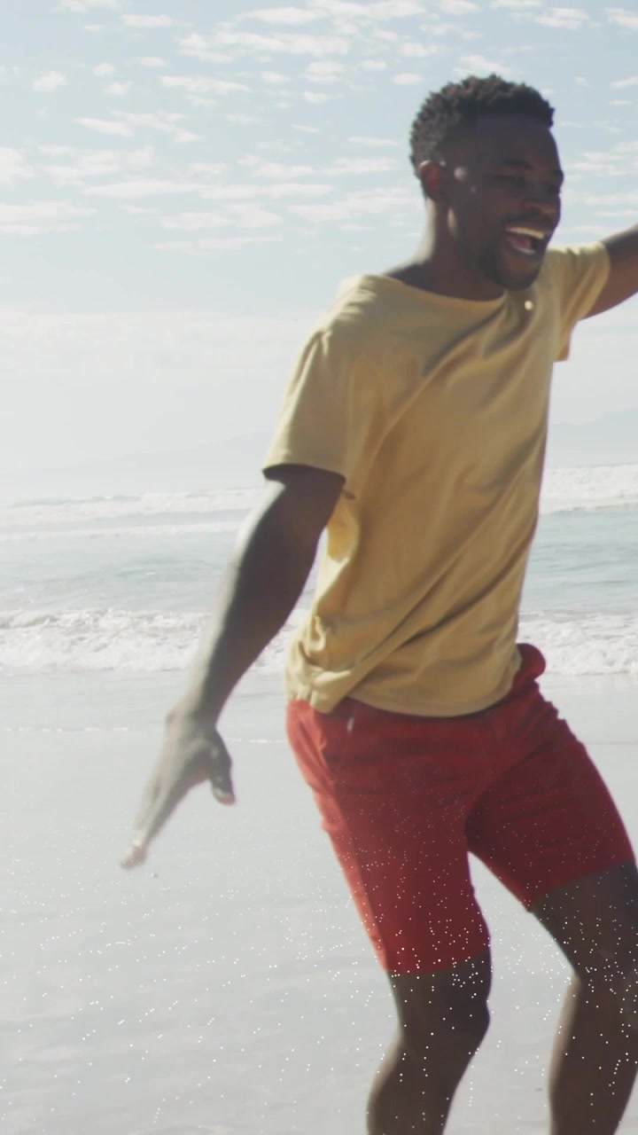 Vertical video: Man stepping into wet sand, balancing and pretending to fly for health content