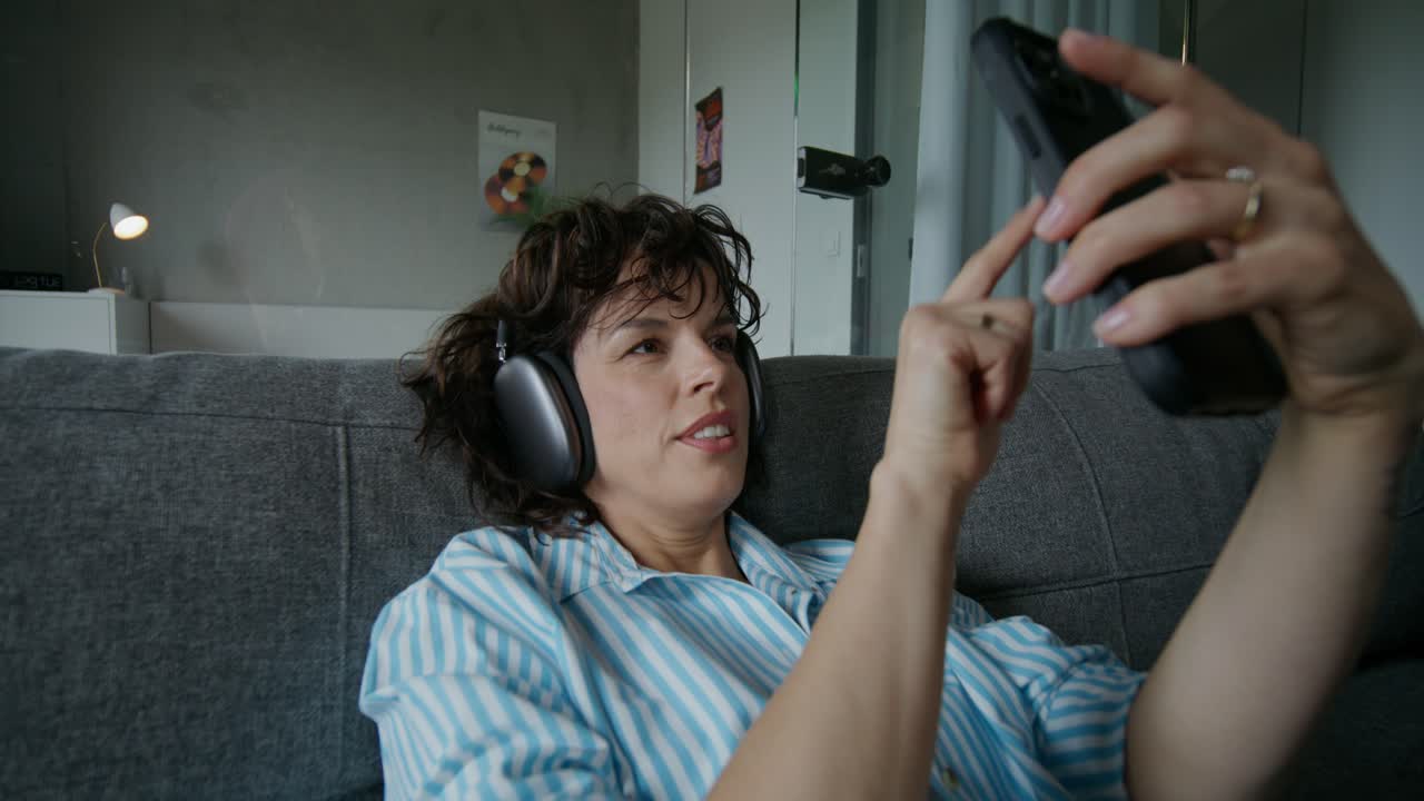 mujer relajándose en el sofá con auriculares y teléfono