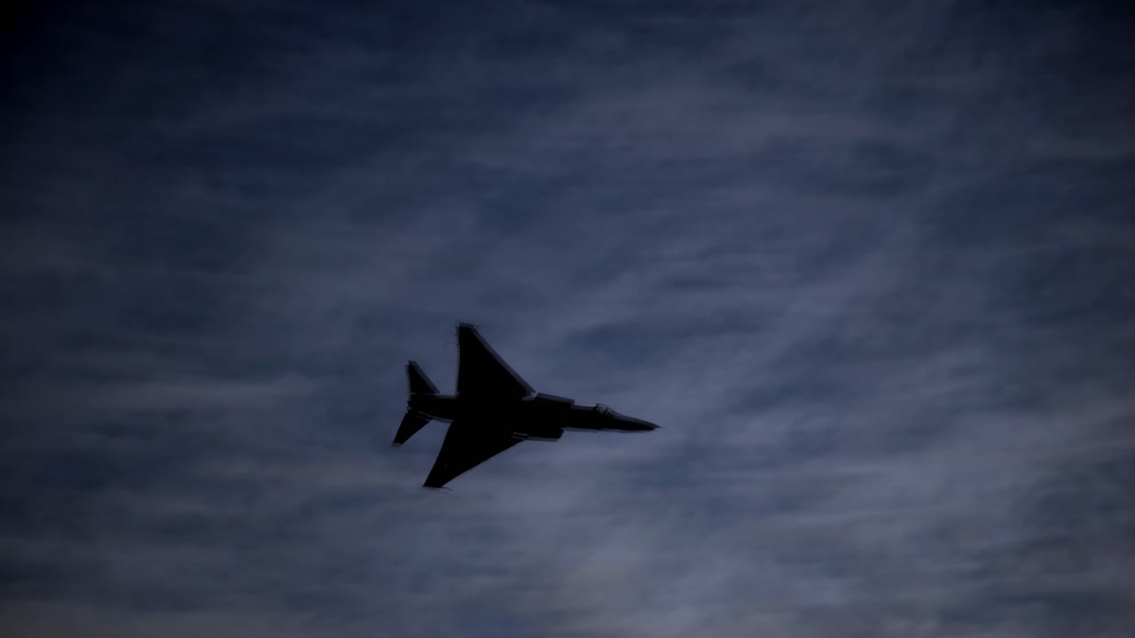 Silhouette of a jet against a cloudy sky, captured from a low angle