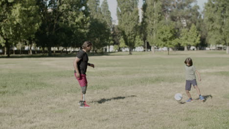 long shot of dad with disability playing ball with son on lawn