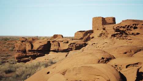 trucking shot with sandstone rock formations and ruined building in background