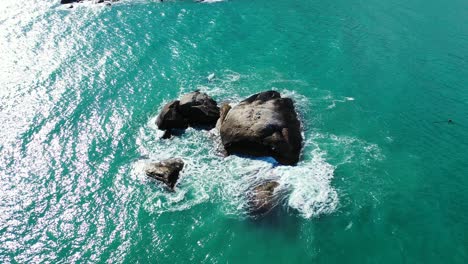 Turquoise-seawater-splashing-on-caved-cliffs-near-rocky-shore-of-tropical-island-at-sunrise-in-Cambodia,-copy-space