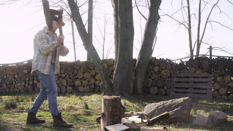 caucasian man chopping firewood with an ax outside a country house